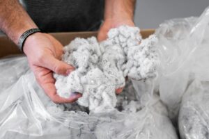 Nahaufnahme wie eine Person weiße Fasern aus PET in der Hand hält