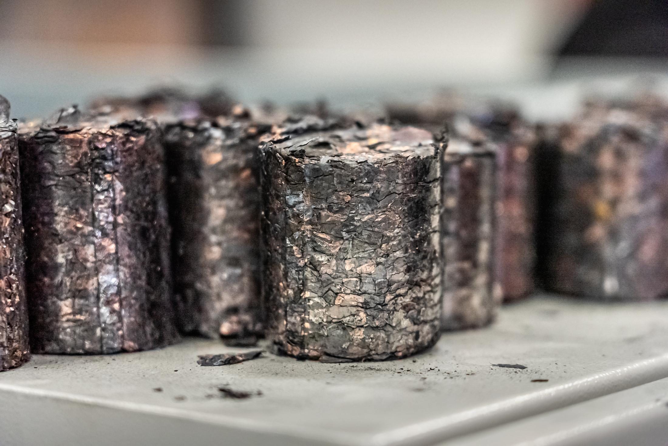 Nahaufnahme mehrerer dunklen Briketts aus Kunststoff und Kupfer