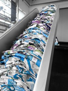 Presslinge aus Milchtüten Tetra Packs werden aus der Maschine im Auswurf geschoben