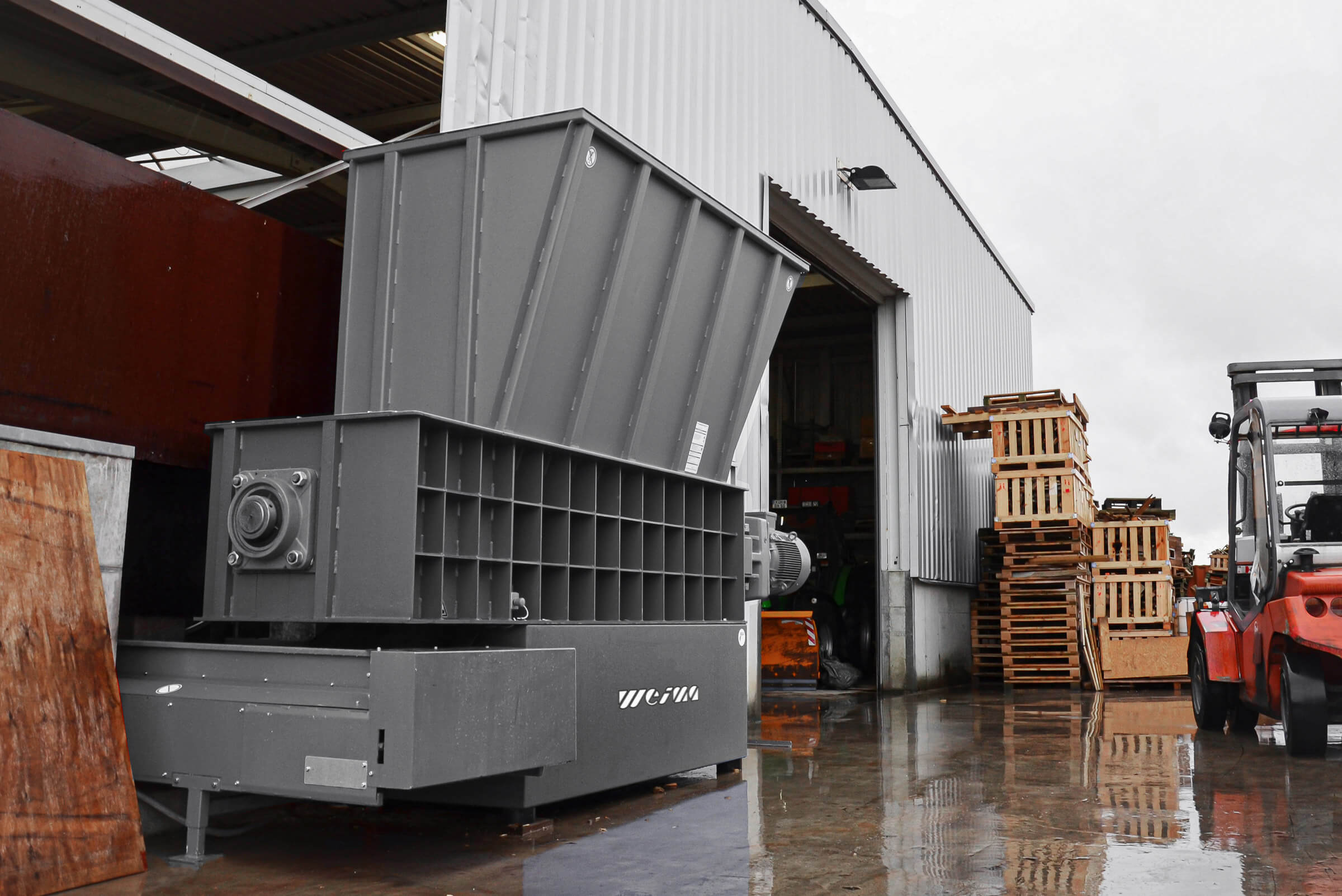 Ein WEIMA Holzwolf auf dem Betriebsgelände bricht Paletten