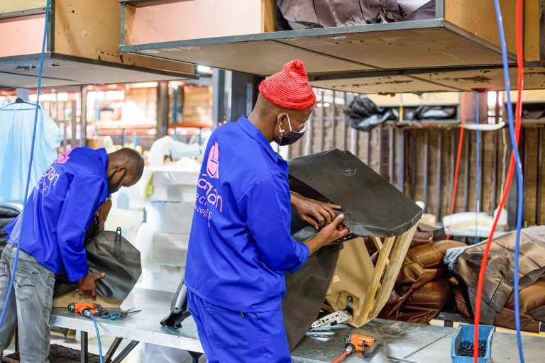 Workers fit upholstery covers onto wooden framed furniture