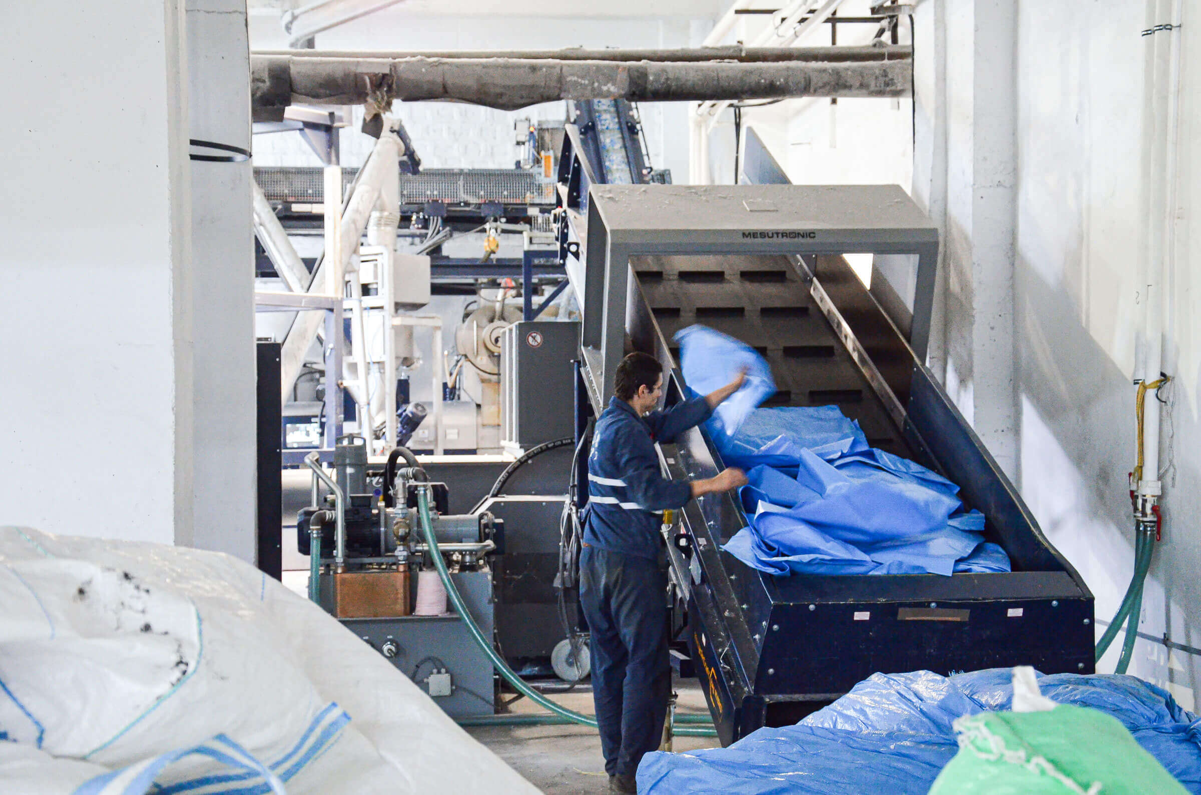 Mitarbeiter befördert Schreddermaterial auf Förderband in den Trichter des WLK1500