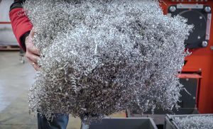 Employee holding bulky piece of aluminum turning scrap