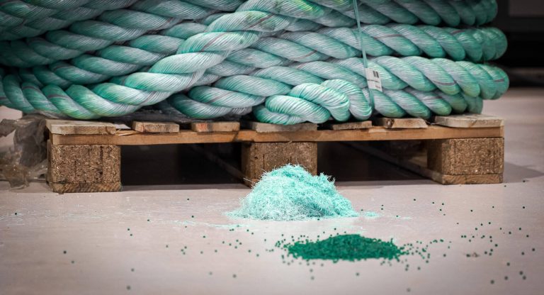 Alte türkise Taue auf Palette, davor zerkleinerte Fasern, davor Regranulat nach der Extrusion