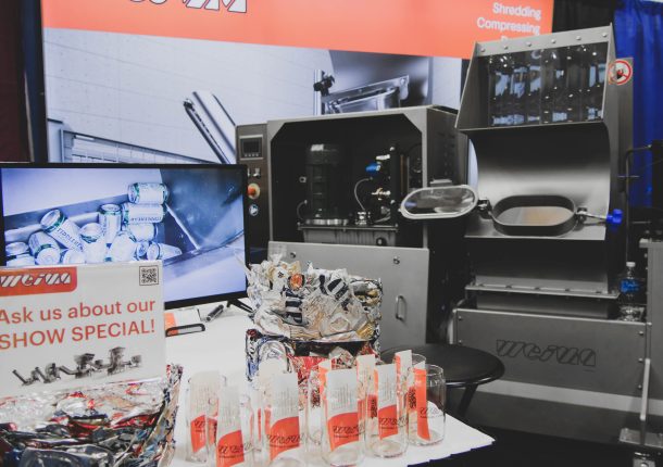 A WEIMA E.200 machine is in a tradeshow booth with a TV and some glasses for giveaways.