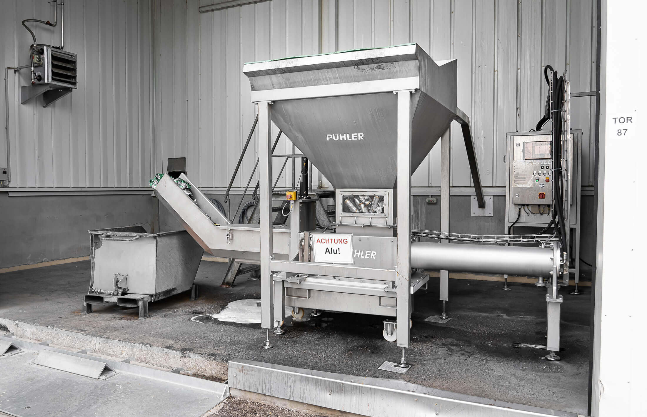 dosen pressmaschine von weima aus edelstahl in einer halle mit kippcontainer