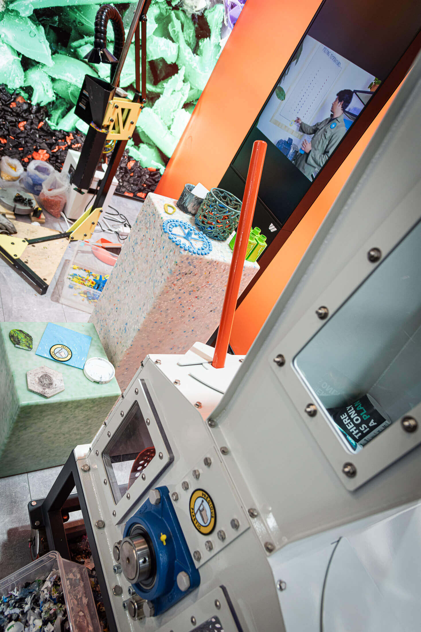 Precious Plastic shredder and injection moulding machine next to a tv screen