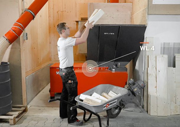 employee fedding the weima wood chipper manually with wood waste
