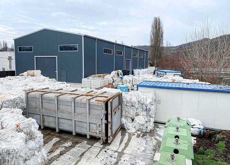 grey production hall and outdoor storage space with baled plastic waste at expert recycling in romania