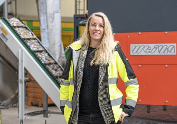 Frau mit Warnjacke vor einem WEIMA Shredder mit Förderband