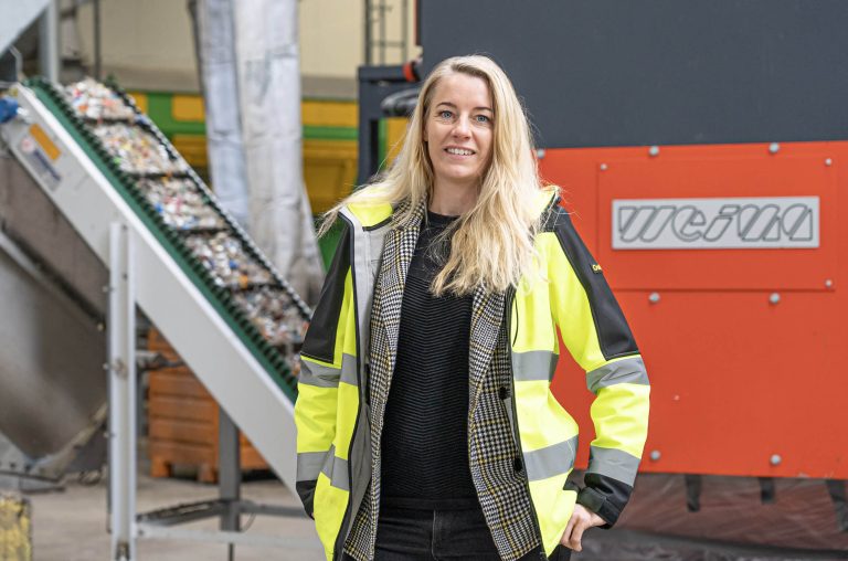 Frau mit Warnjacke vor einem WEIMA Shredder mit Förderband