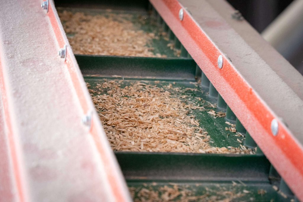 green conveyor belt with wood chips