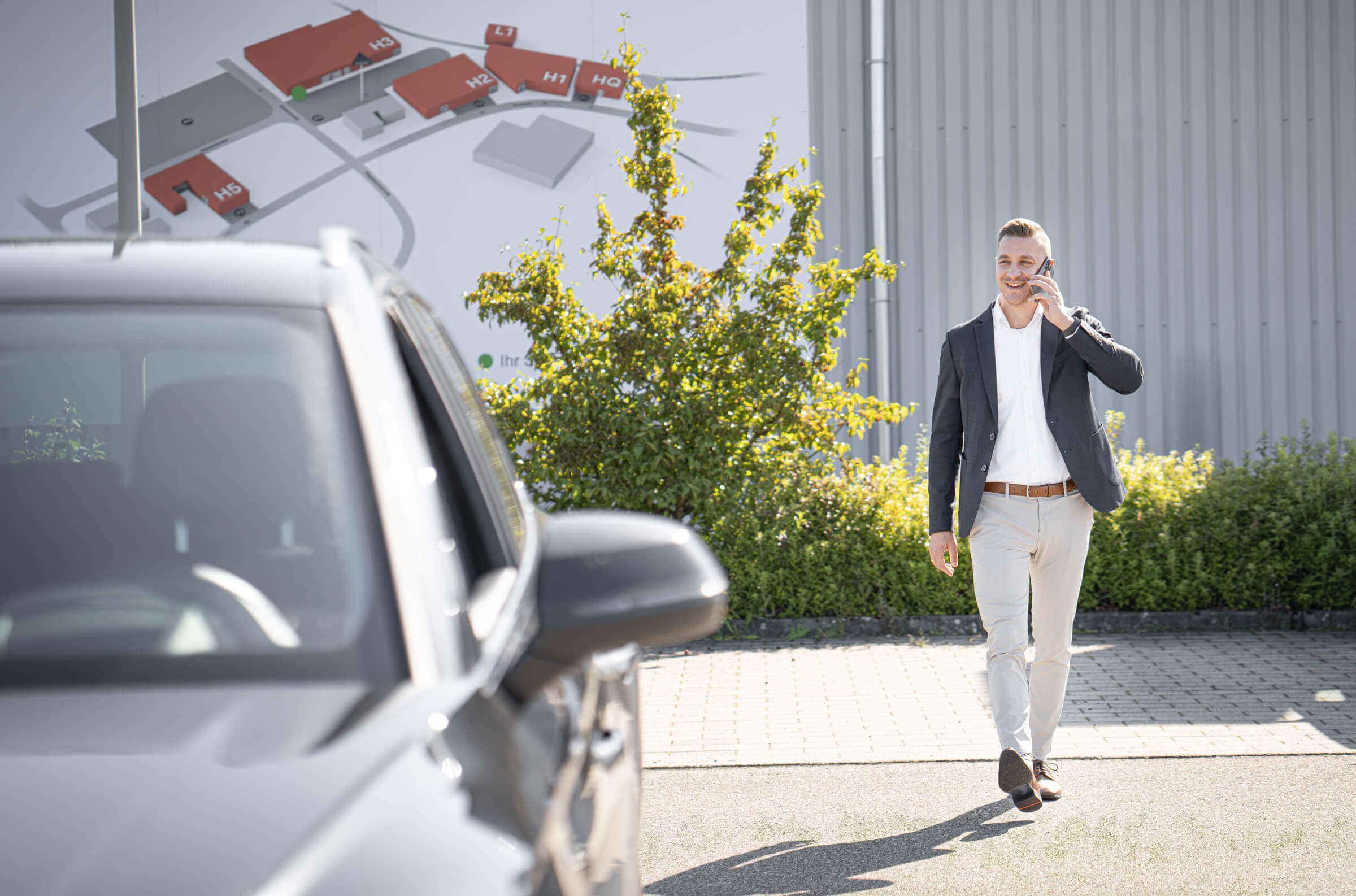 Sales Manager bei WEIMA auf einem Parkplatz neben Auto
