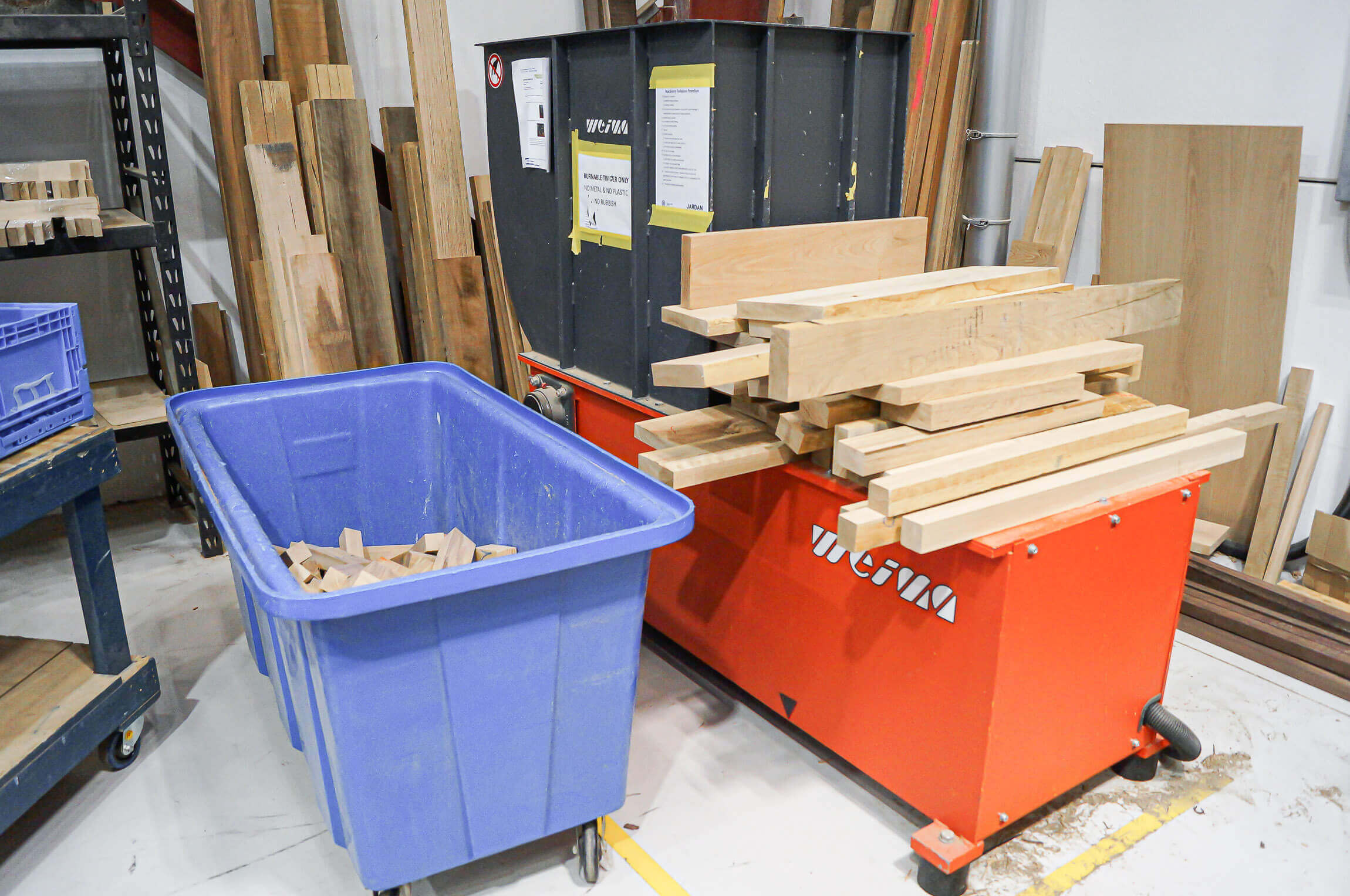 A red-orange Shredder with a blue box of wood waste and input material