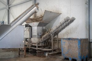 Eine silberne Entwässerungspresse aus Edelstahl bei der Entwässerung von Kunststoff Feinanteilen in einer Industriehalle