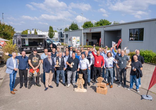 A group of smiling men in front of a company building.