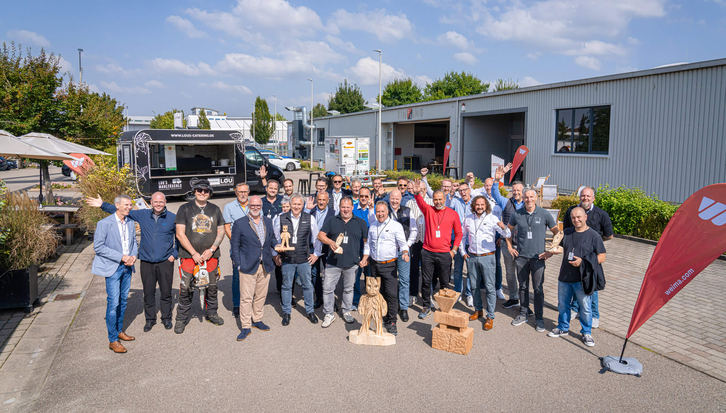 A group of smiling men in front of a company building.