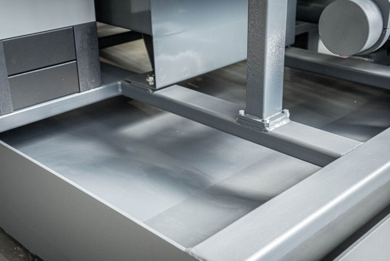 A gray collecting tray under a briquetting press