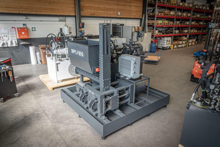 A gray briquetting press in a warehouse