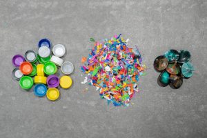 Three piles: Bottle caps, shredded bottle caps, spinning tops made from bottle caps