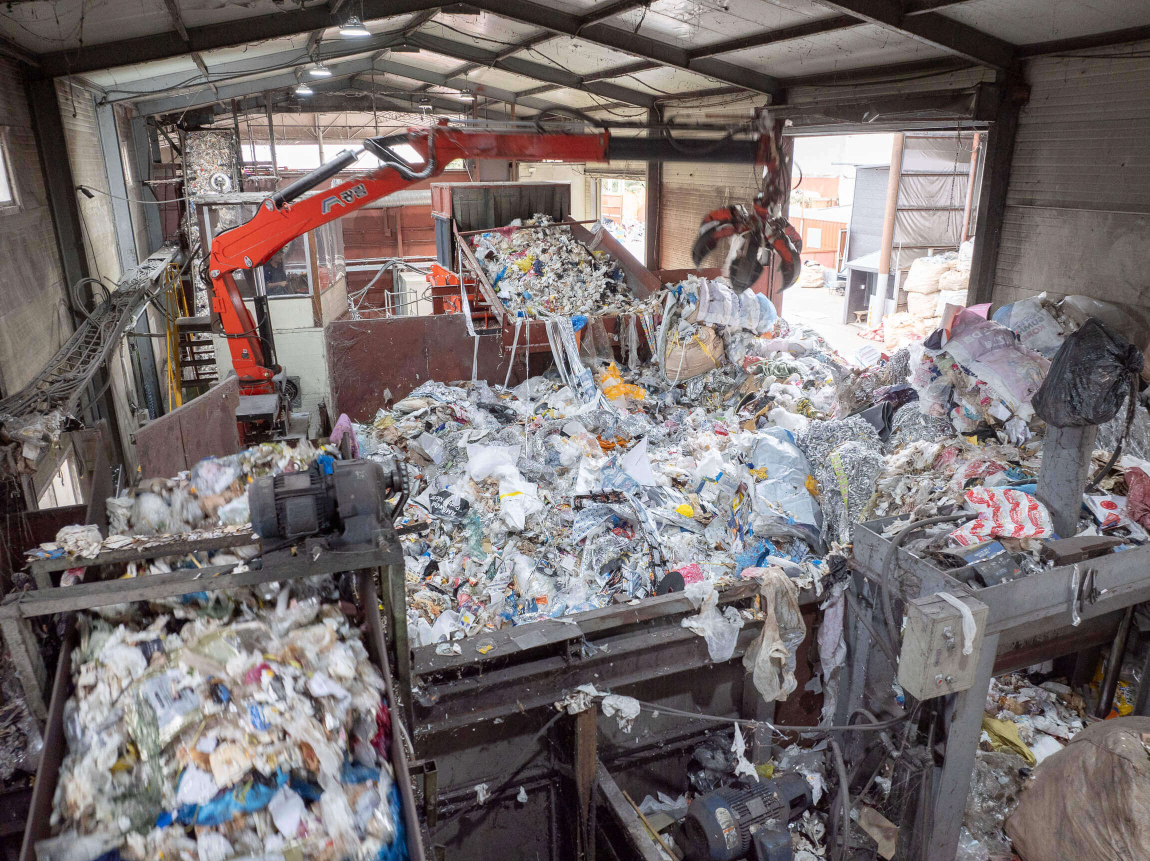 View of the large amount of waste being transported to the shredder by conveyor belts and crane