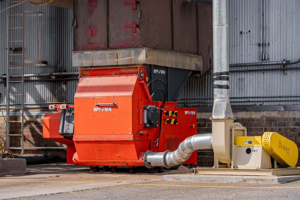 A close-up photo of the WEIMA shredder behind the warehouse.