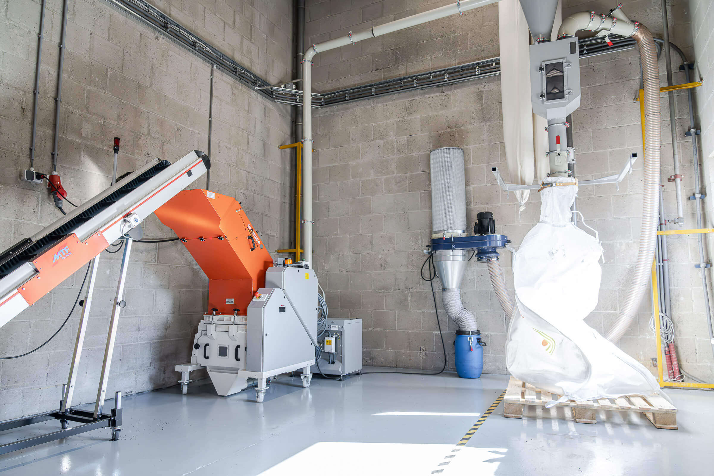 Wanner Dynamic-Serie Granulator zur Nachzerkleinerung von PVC Reststoffen, rechts daneben eine Entstaubungsanlage