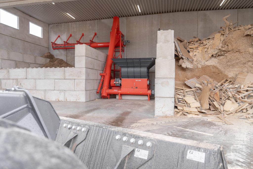 General view of the plant in the Trier firewood factory with WEIMA shredder, red Steiner screw conveyor and large waste wood storage area.