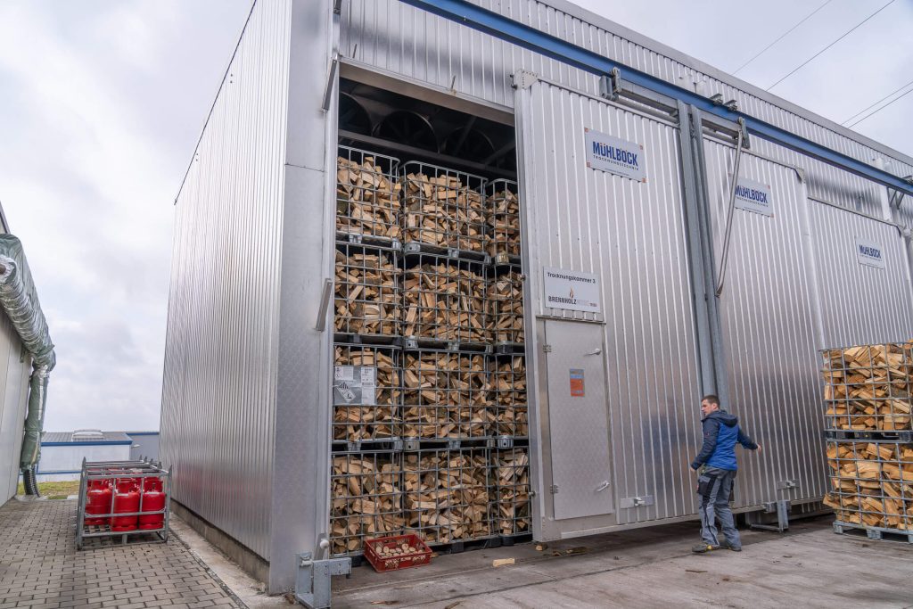 Stacked wire mesh boxes with kiln-dried firewood in the warehouse of the Trier firewood factory.