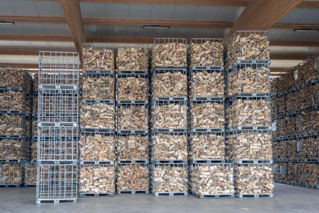 Stacked wire mesh boxes with kiln-dried firewood in the warehouse of the Trier firewood factory.