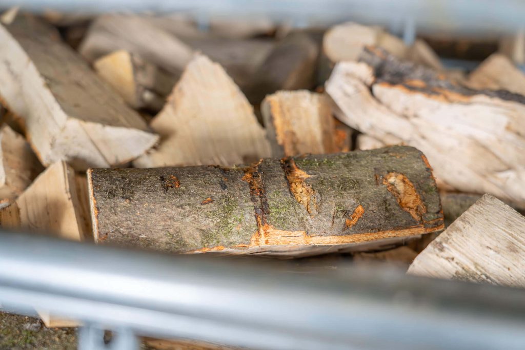 Split, dry firewood in a wire mesh box.