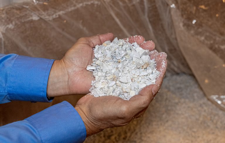 A person holds shredded, white recycling material in their hands.
