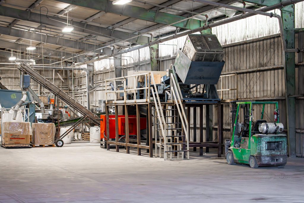 An industrial shredder system with feed system and conveyor belt is set up in a spacious workshop.