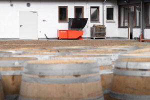 In the background, an orange shredder from WEIMA; in the foreground, barrique barrels.