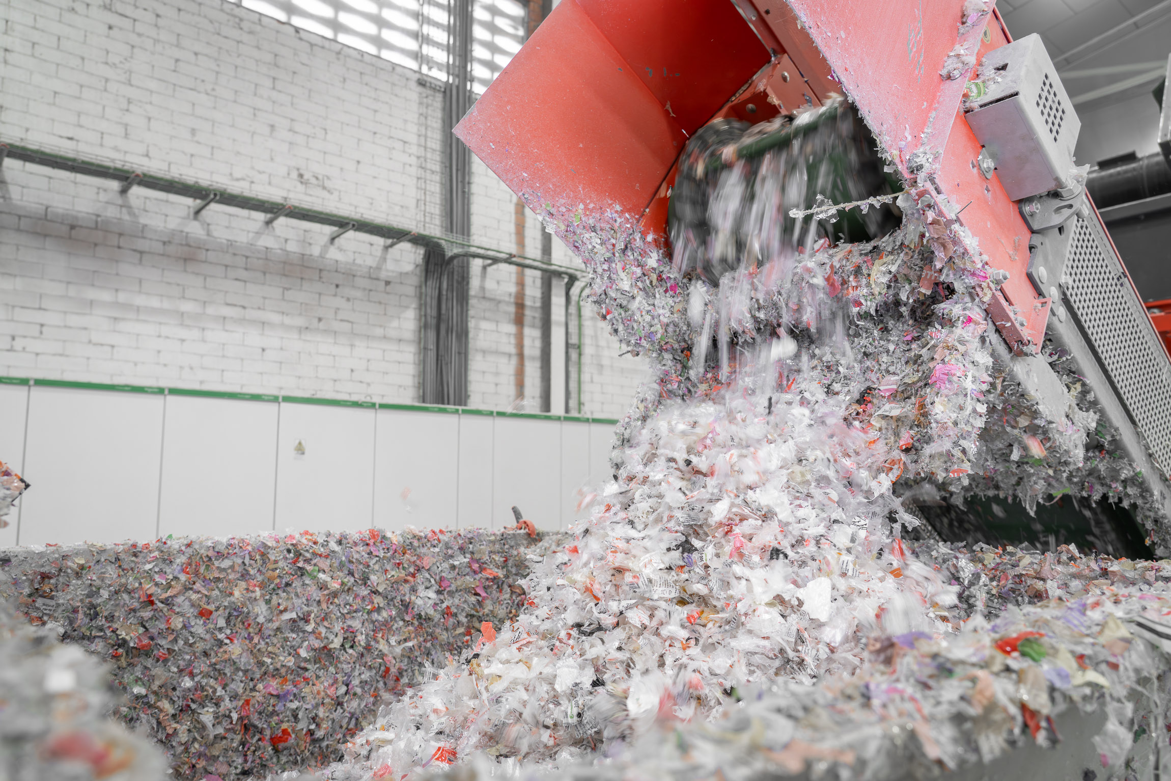 Man sieht wie aus dem Shredder die zerkleinerten Polypropylen- und Polyethylen-Resten fallen